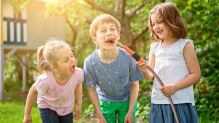 Kinder trinken frisches Wasser aus dem Wasserschlauch