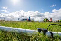 Helikopter für die Befliegung im Hintergrund und im Vordergrund der weiße Magnetometer.